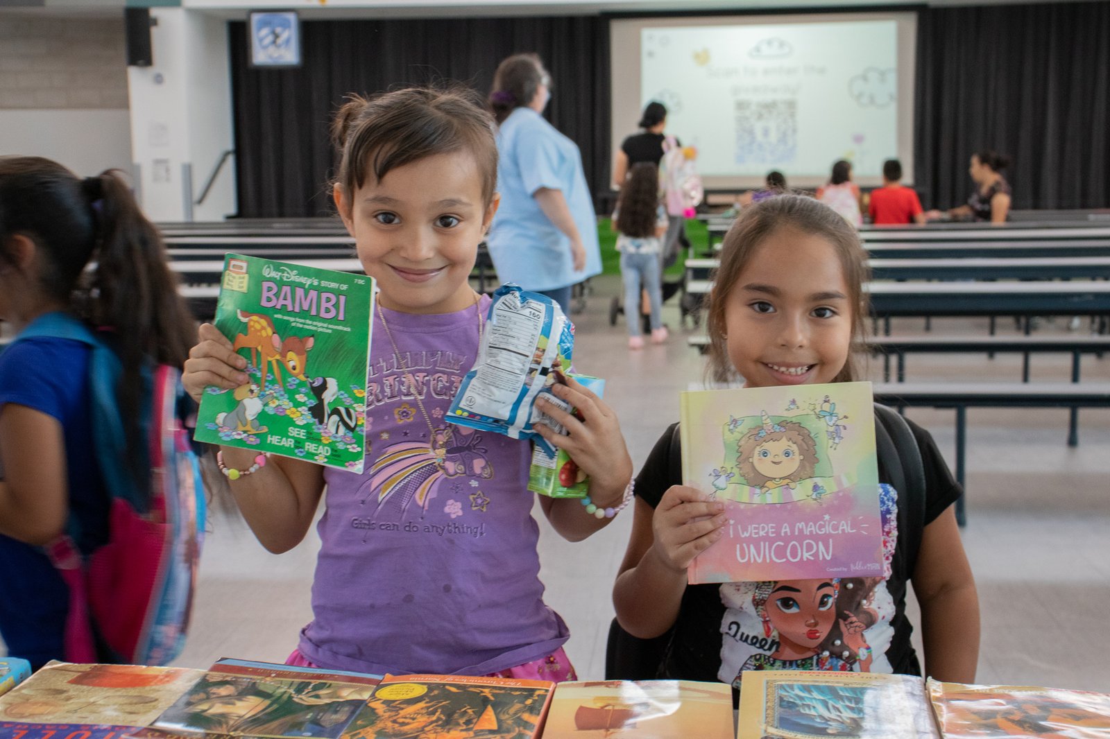 two young girls smiling with books in their hands